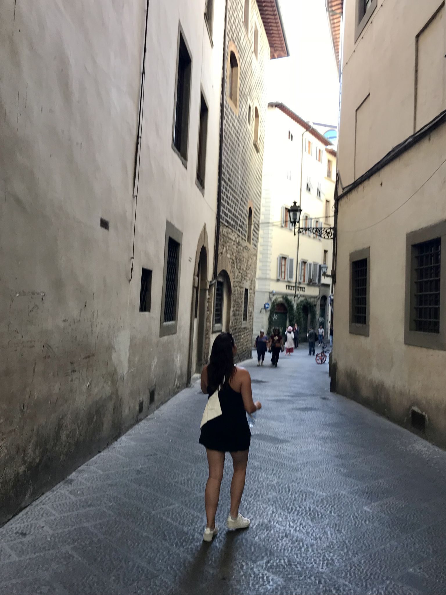 Ulana Rey PharmD walking a narrow stone lane in Florence at dusk.